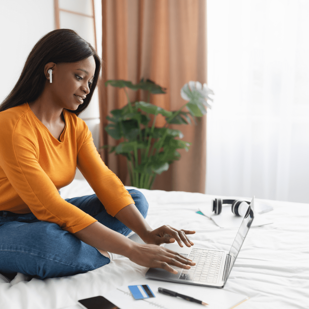 a brown woman typing on a laptop at home for the ladies weekend write in workshop